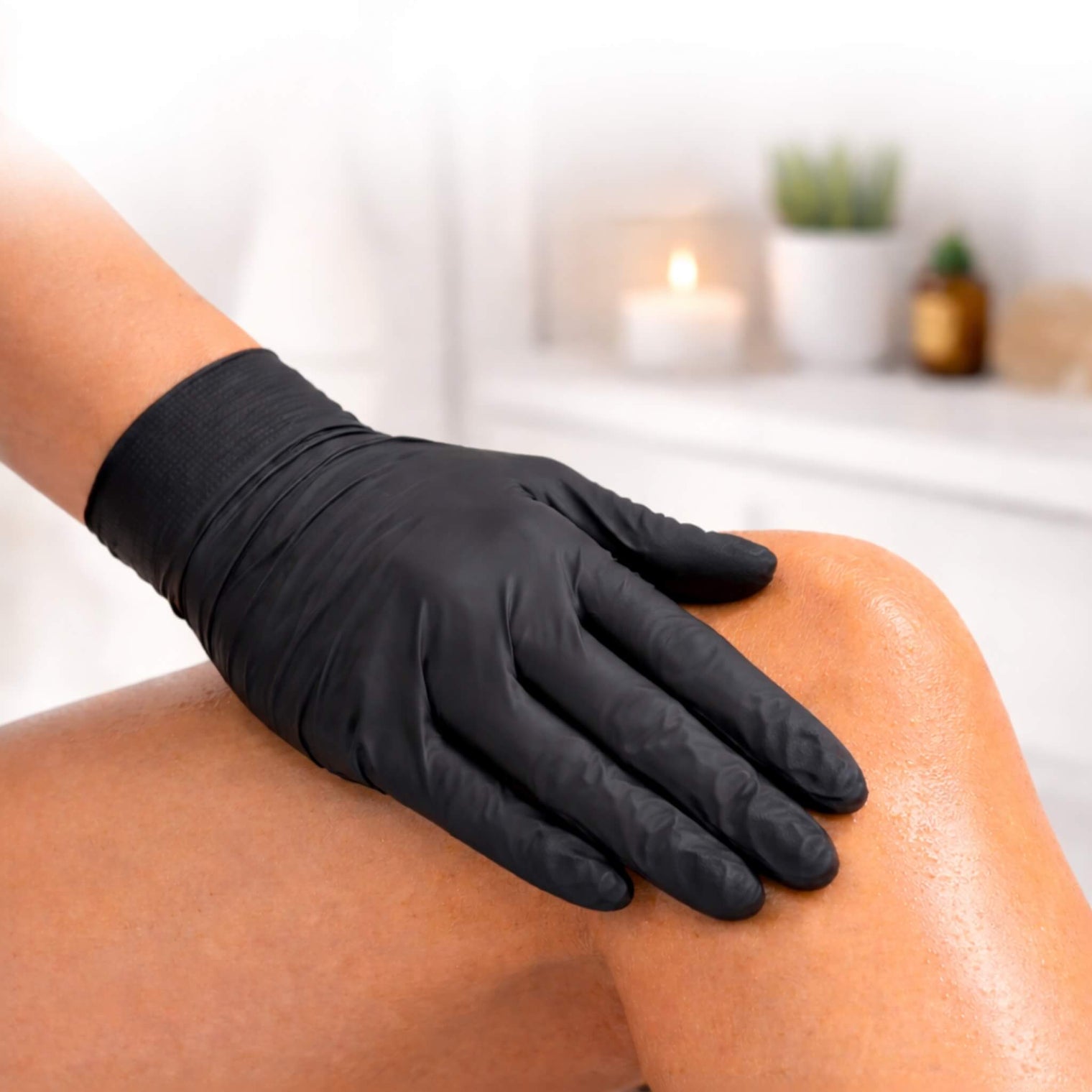 Black nitrile tanning glove applying self tanner to leg for smooth, streak-free application