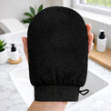 Venice Gold exfoliating mitt held in hand, black textured body scrub mitt for pre-tan exfoliation and smooth skin